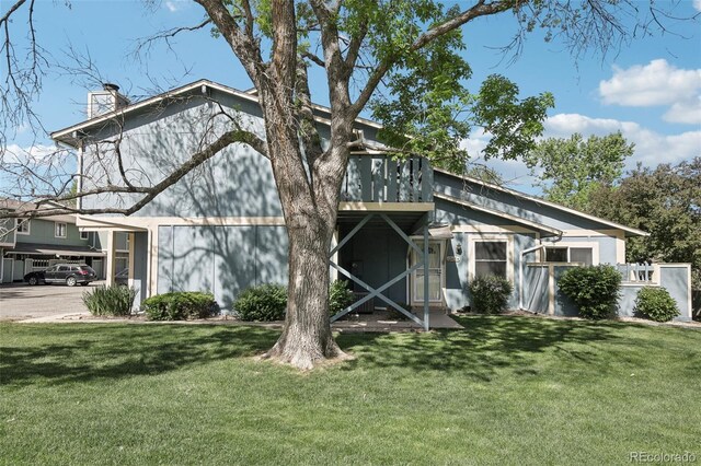 12115 Bannock St Unit B, Denver, CO 80234 - rear view of house featuring a chimney, a yard, and a carport