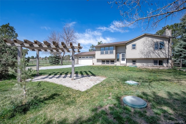 back of property with a garage, a pergola, a chimney, concrete driveway, and a lawn