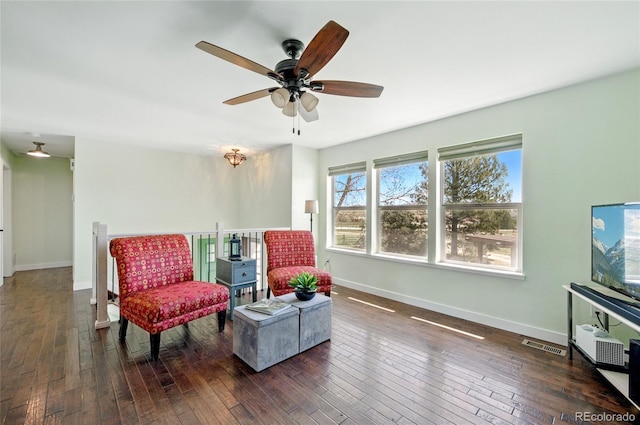living area with a ceiling fan, baseboards, visible vents, and hardwood / wood-style floors
