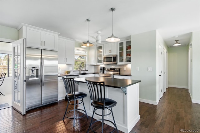 kitchen featuring a sink, dark countertops, stainless steel appliances, and dark wood-type flooring