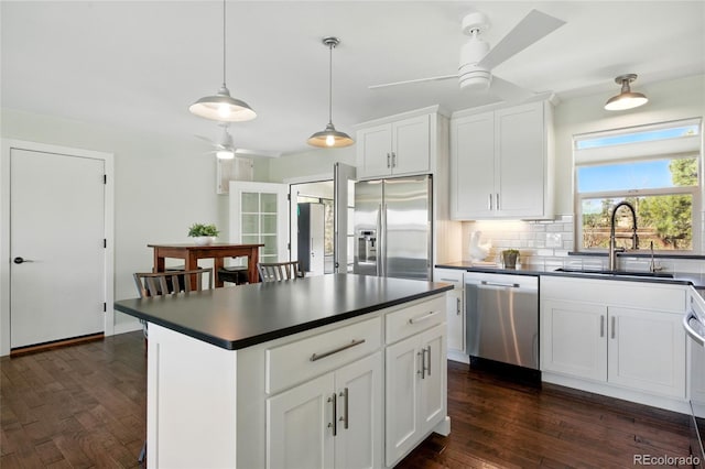 kitchen featuring a sink, dark wood-style flooring, dark countertops, a ceiling fan, and stainless steel appliances