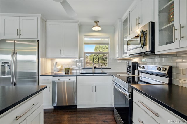 kitchen featuring a sink, dark countertops, stainless steel appliances, and white cabinetry