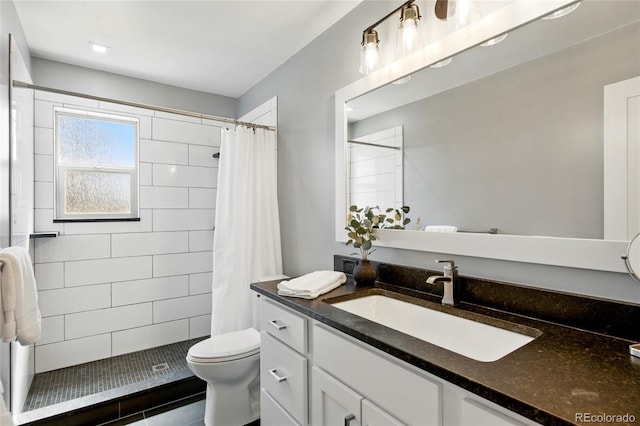bathroom with vanity, a tile shower, and toilet