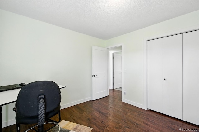 unfurnished office with a textured ceiling, baseboards, and wood finished floors