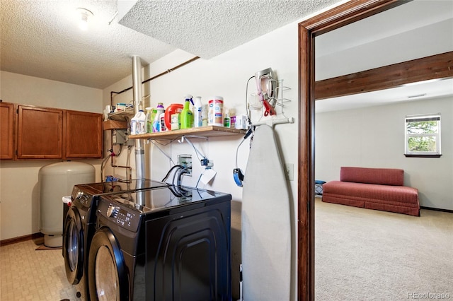 laundry area with a textured ceiling, independent washer and dryer, cabinet space, baseboards, and light carpet