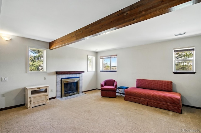 living room with baseboards, beam ceiling, carpet, and a tile fireplace