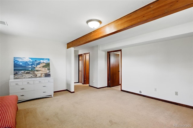 unfurnished bedroom featuring baseboards, light carpet, and beam ceiling