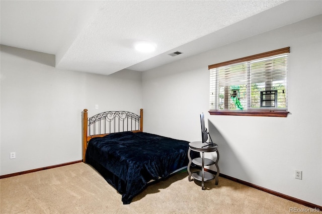 bedroom with a textured ceiling, visible vents, baseboards, and carpet