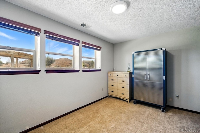 bedroom featuring a textured ceiling, baseboards, visible vents, and light carpet