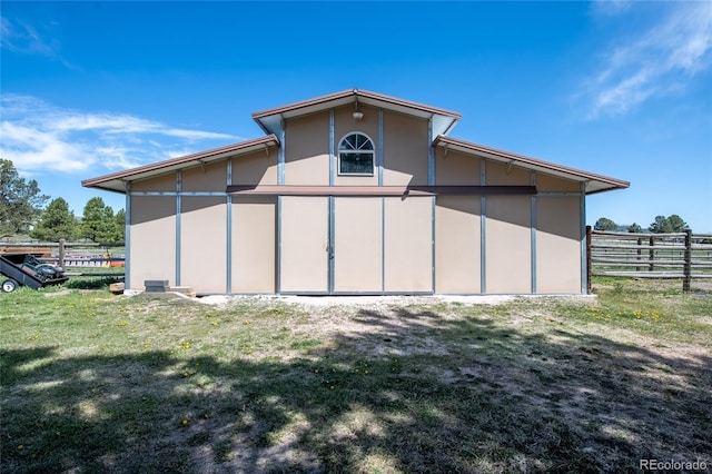rear view of house featuring a yard, fence, and stucco siding