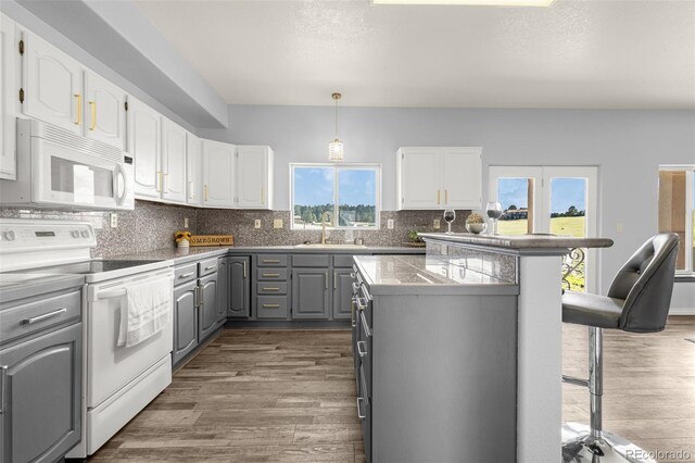 12255 Forest Green Dr, Elbert, CO 80106 - kitchen with white appliances, gray cabinetry, white cabinets, and a breakfast bar area