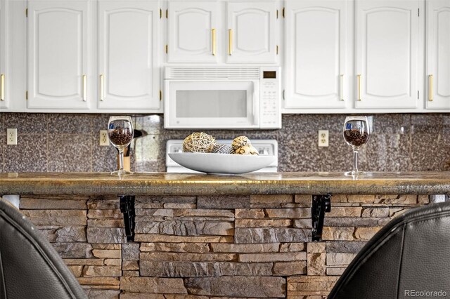 12255 Forest Green Dr, Elbert, CO 80106 - kitchen featuring white microwave, white cabinetry, and backsplash