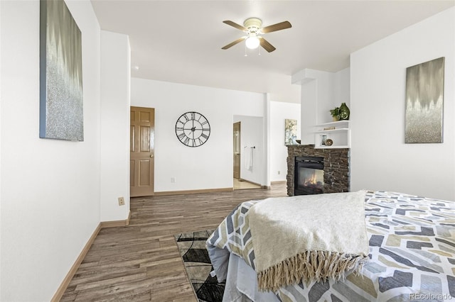 12255 Forest Green Dr, Elbert, CO 80106 - bedroom with wood finished floors, baseboards, a stone fireplace, and a ceiling fan