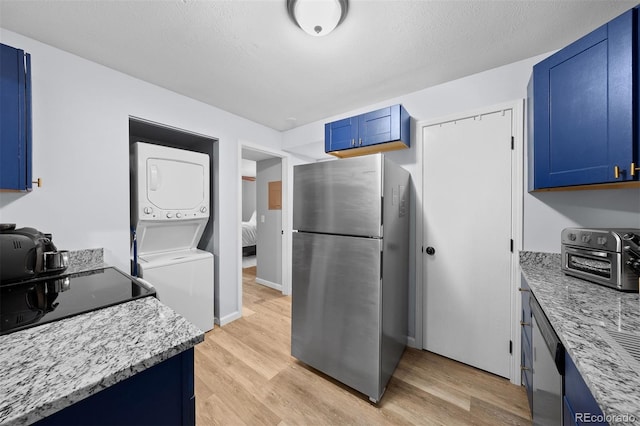 311 W Lehow Ave Unit 3, Englewood, CO 80110 - kitchen with stacked washer / dryer, light wood-type flooring, appliances with stainless steel finishes, and blue cabinetry