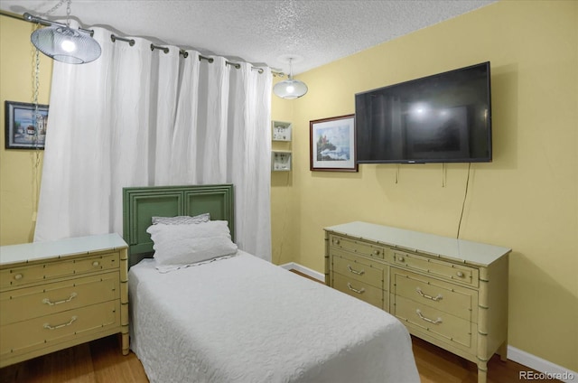 bedroom with dark wood-style floors, baseboards, and a textured ceiling