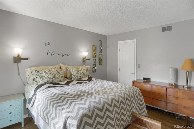 bedroom with dark wood-style flooring, visible vents, and a textured ceiling