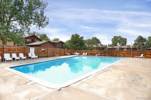 community pool with a fenced backyard and a patio