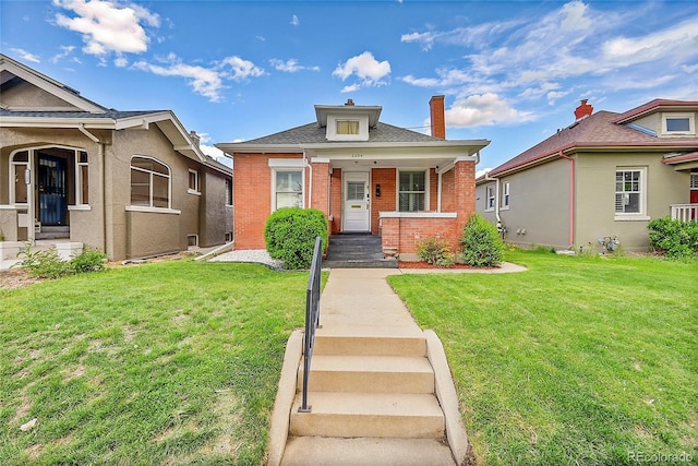 bungalow with a chimney, a front yard, and brick siding