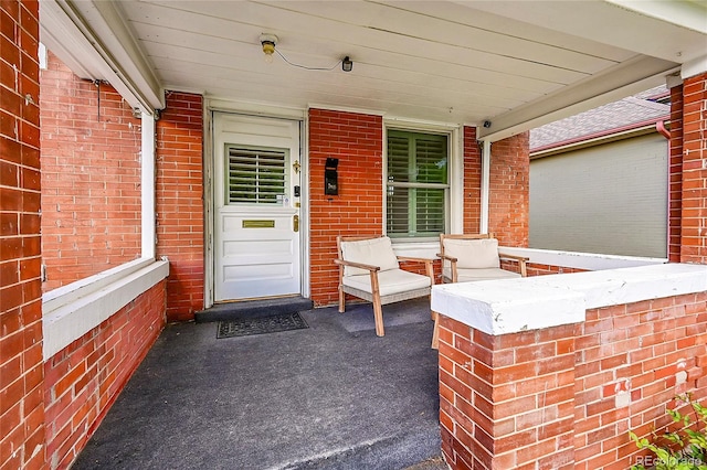 doorway to property with brick siding and covered porch