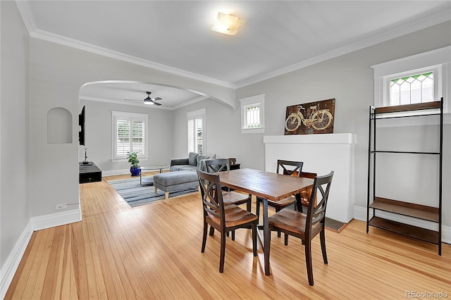 dining space with light wood-style floors, arched walkways, and a wealth of natural light