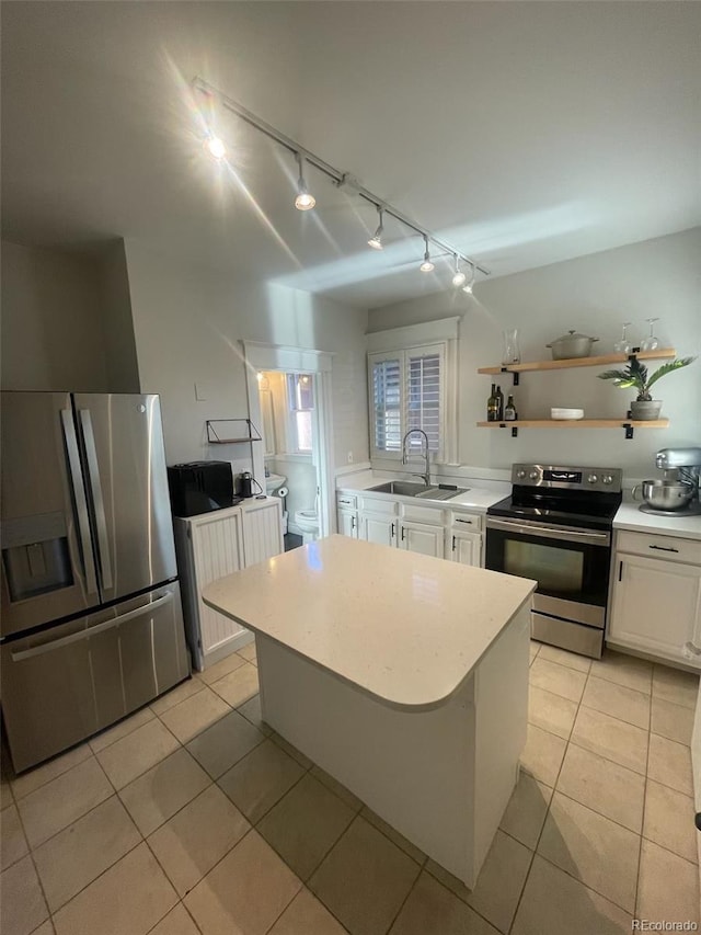 kitchen featuring a sink, track lighting, light countertops, stainless steel appliances, and white cabinetry