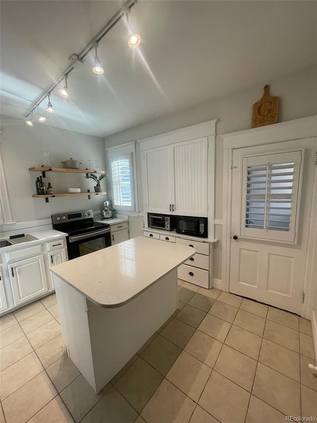 kitchen with stainless steel electric stove, light tile patterned floors, white cabinets, and rail lighting