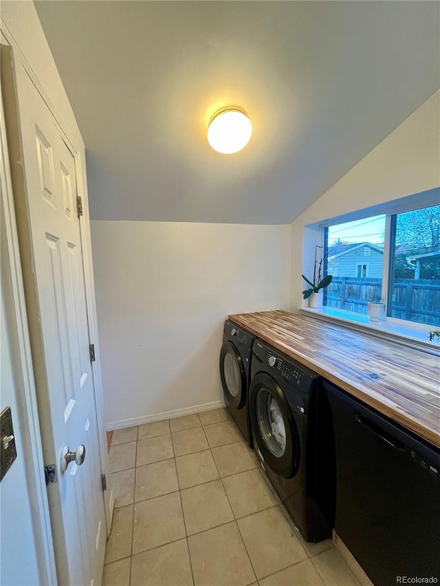 clothes washing area featuring baseboards, laundry area, light tile patterned flooring, and washer and clothes dryer