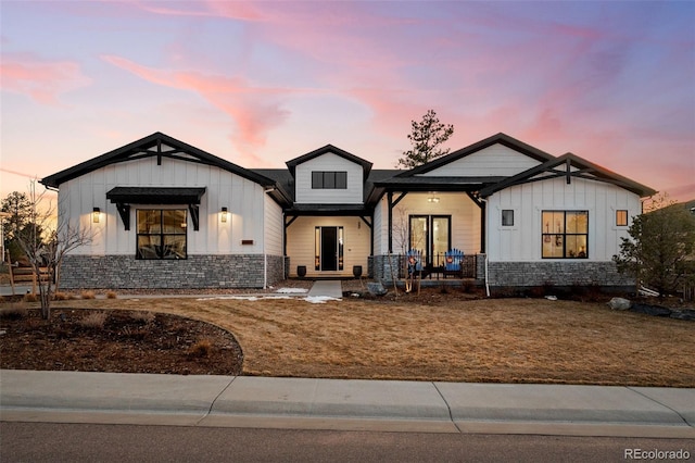 modern farmhouse with covered porch, board and batten siding, and stone siding