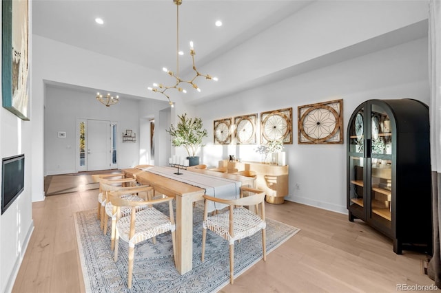 dining area featuring a notable chandelier, a glass covered fireplace, recessed lighting, light wood-style floors, and baseboards