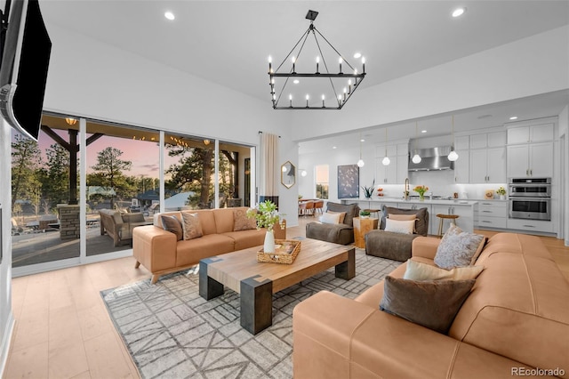 living area featuring a notable chandelier, recessed lighting, light wood-type flooring, and a towering ceiling