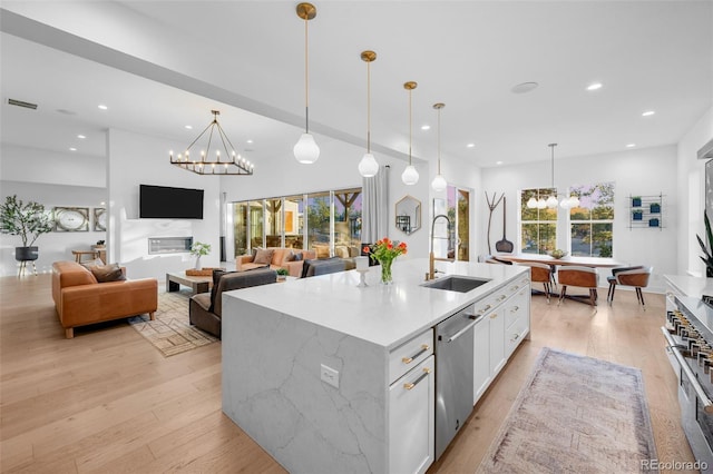 kitchen with light wood-style flooring, a sink, stainless steel dishwasher, an inviting chandelier, and white cabinets