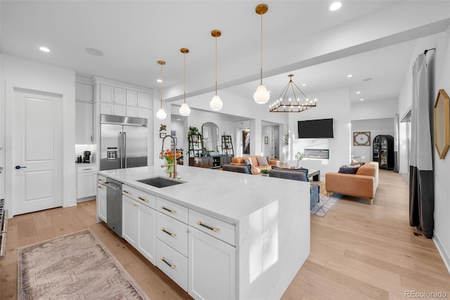 kitchen with light wood-style flooring, arched walkways, appliances with stainless steel finishes, and a sink