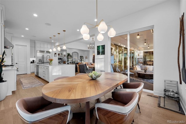 dining room with visible vents, light wood-style flooring, recessed lighting, arched walkways, and a notable chandelier