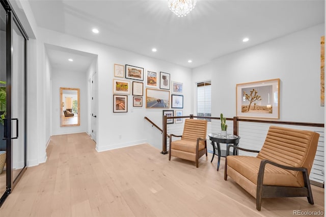 living area with baseboards, an inviting chandelier, recessed lighting, light wood-style floors, and an upstairs landing