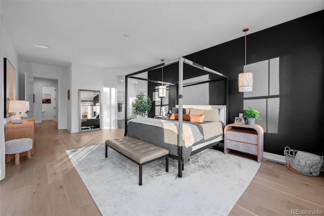 bedroom with light wood finished floors, visible vents, and baseboards