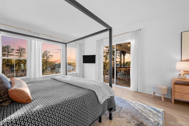 bedroom featuring access to outside, wood finished floors, and baseboards