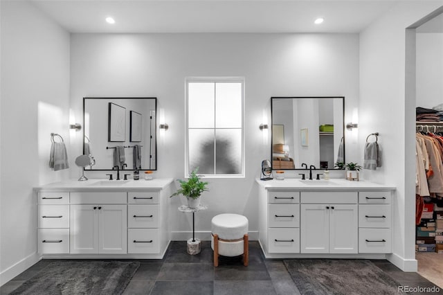 bathroom with two vanities, baseboards, and a sink