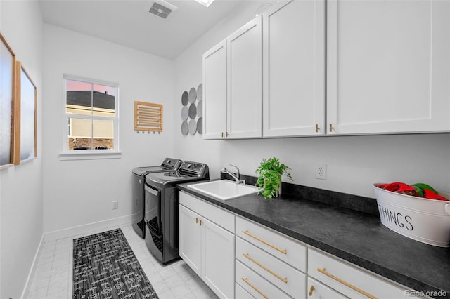 washroom with visible vents, washer and clothes dryer, a sink, cabinet space, and baseboards