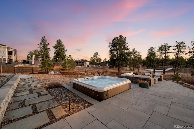 patio terrace at dusk featuring hot tub deck surround and an outdoor hangout area