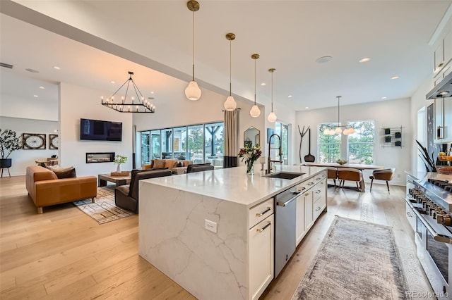 kitchen with a sink, a chandelier, white cabinetry, dishwasher, and light wood-style floors