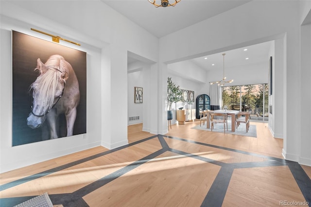 hallway featuring baseboards, wood finished floors, a chandelier, and recessed lighting