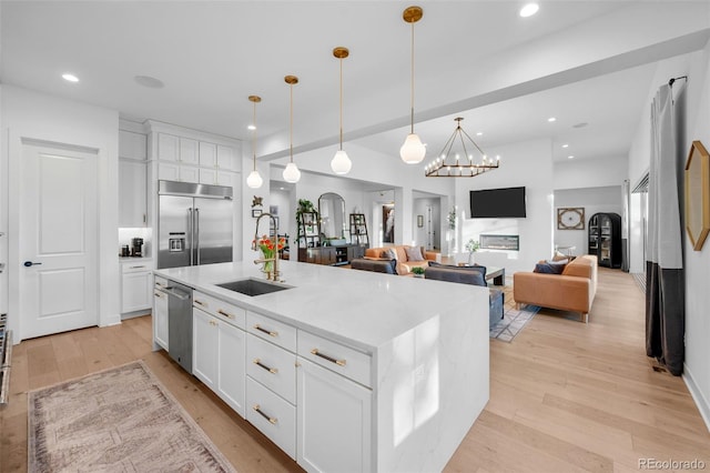 kitchen with white cabinetry, a sink, stainless steel appliances, and light wood-type flooring