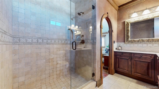 bathroom with vanity, ornamental molding, tasteful backsplash, walk in shower, and tile walls