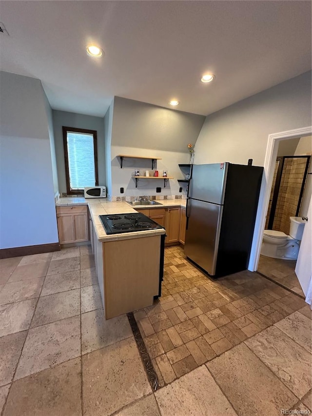 kitchen featuring light brown cabinetry, black electric cooktop, stainless steel refrigerator, and kitchen peninsula