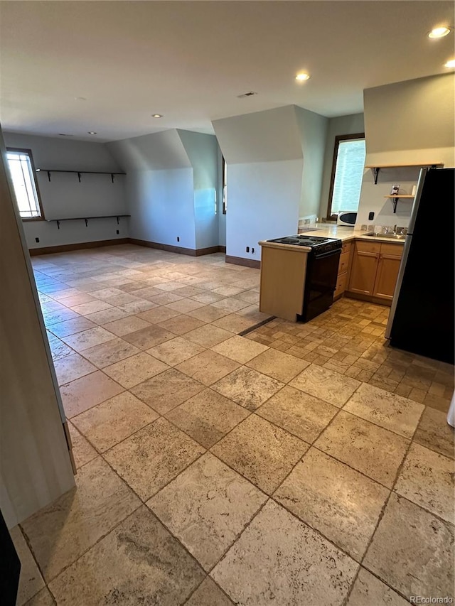 kitchen featuring black range oven, stainless steel fridge, kitchen peninsula, and a wealth of natural light