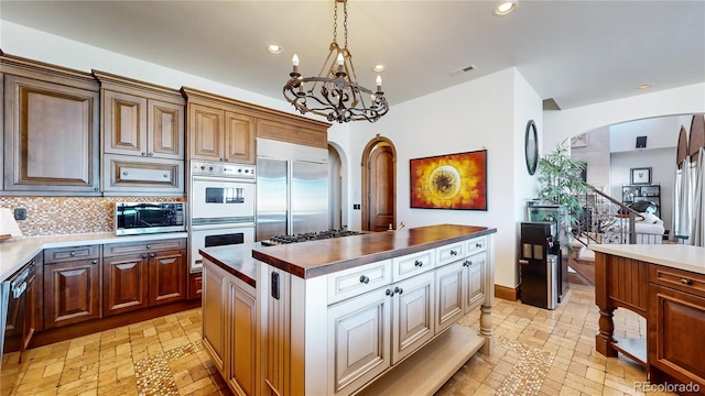 kitchen featuring pendant lighting, tasteful backsplash, a chandelier, stainless steel appliances, and a center island