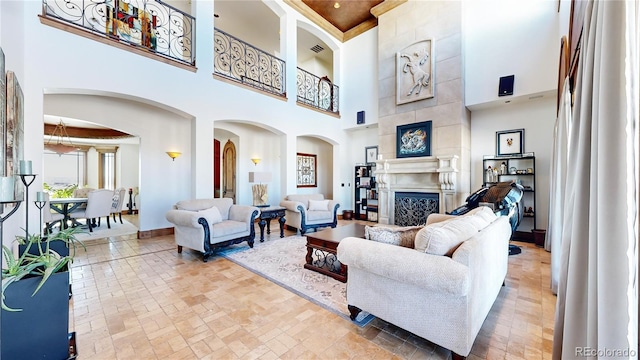 living room with a towering ceiling and a tiled fireplace