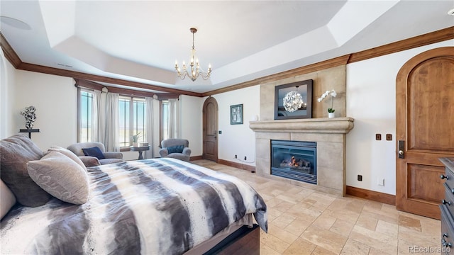 bedroom with crown molding, a tray ceiling, a tiled fireplace, and a notable chandelier