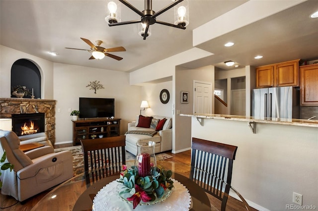 dining area with a ceiling fan, baseboards, dark wood finished floors, recessed lighting, and a stone fireplace