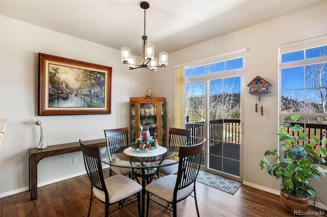 dining area with baseboards, wood finished floors, and a chandelier